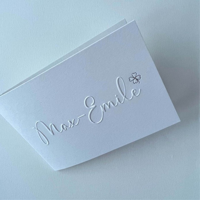 Minimalistisch geboortekaartje met reliëfdruk en zilveren klavertje