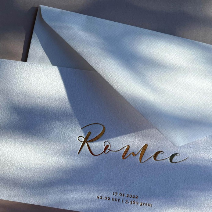 Klassiek geboortekaartje op suede stof met sierlijke letters in luxe goudfolie