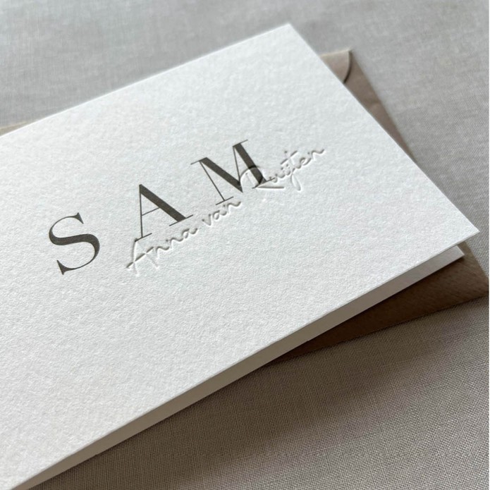 Minimalistisch geboortekaartje met voelbare achternaam in reliëfdruk